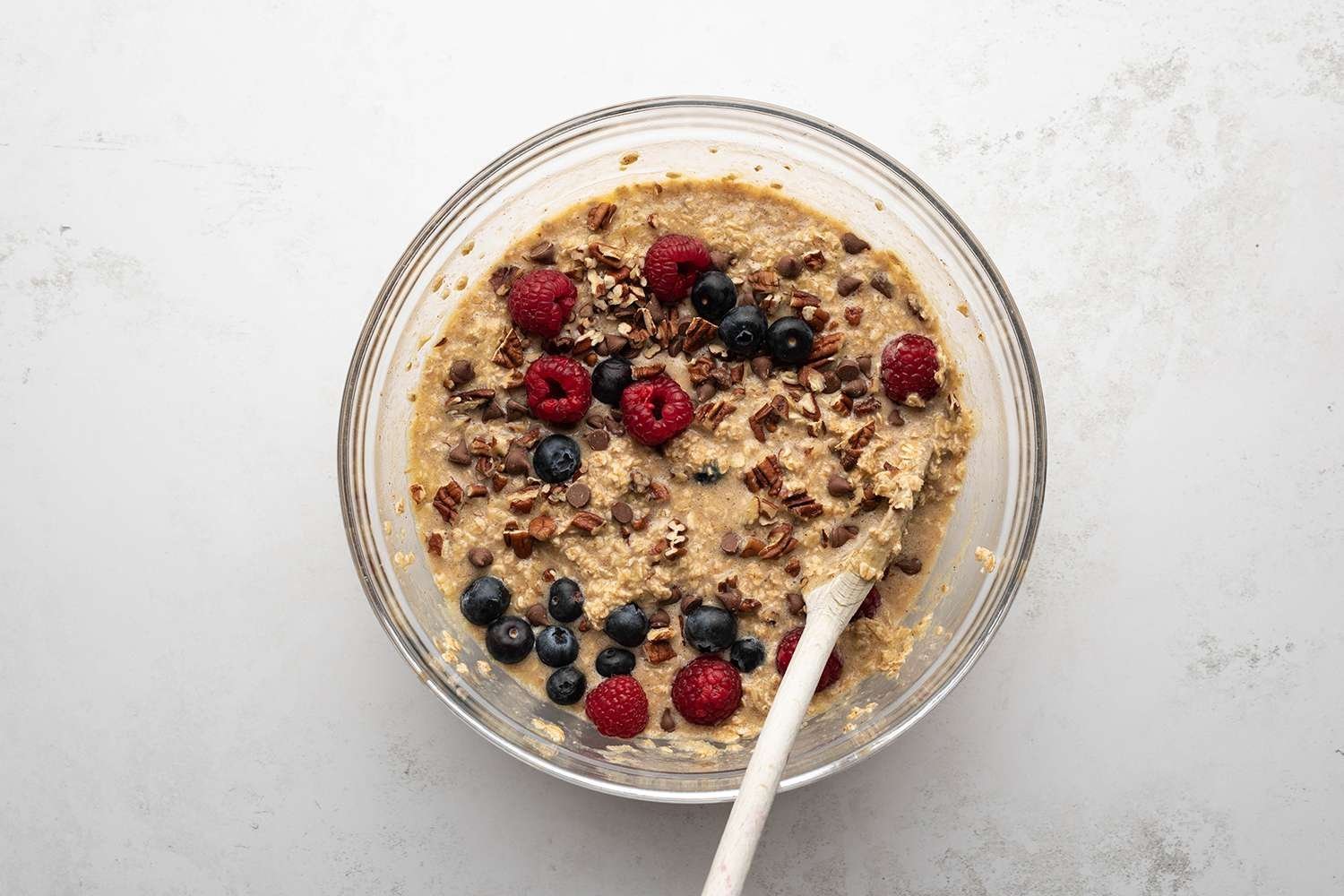 Oatmeal with berries and nuts in a bowl, with a wooden spoon 