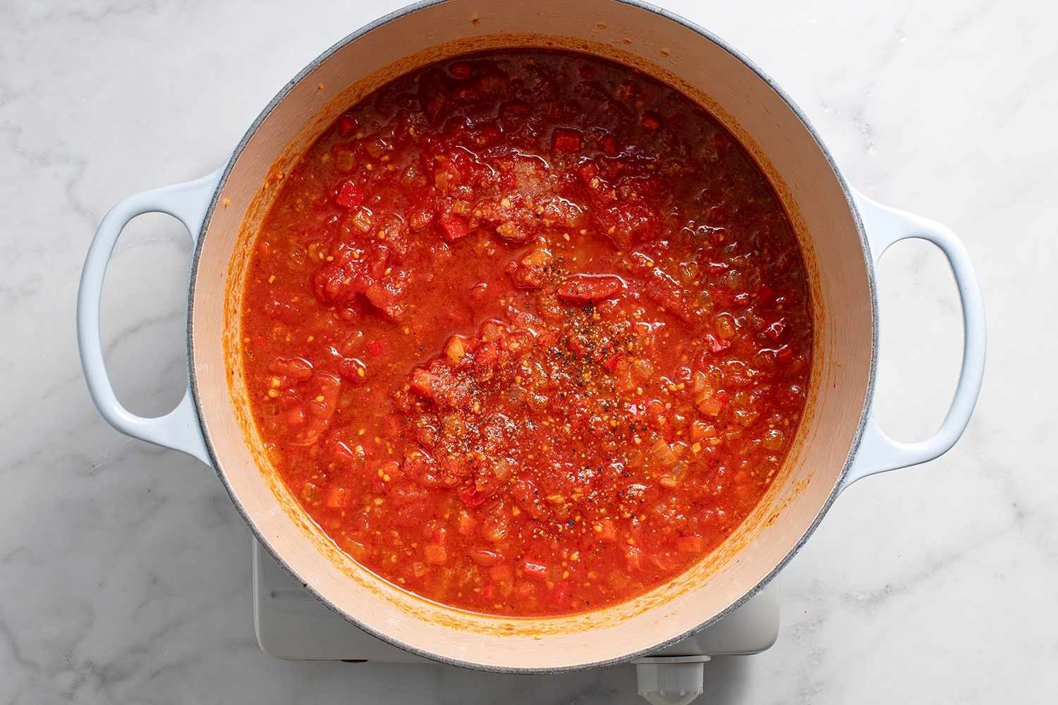 Tomatoes and their juice added to the spice mixture in the pot