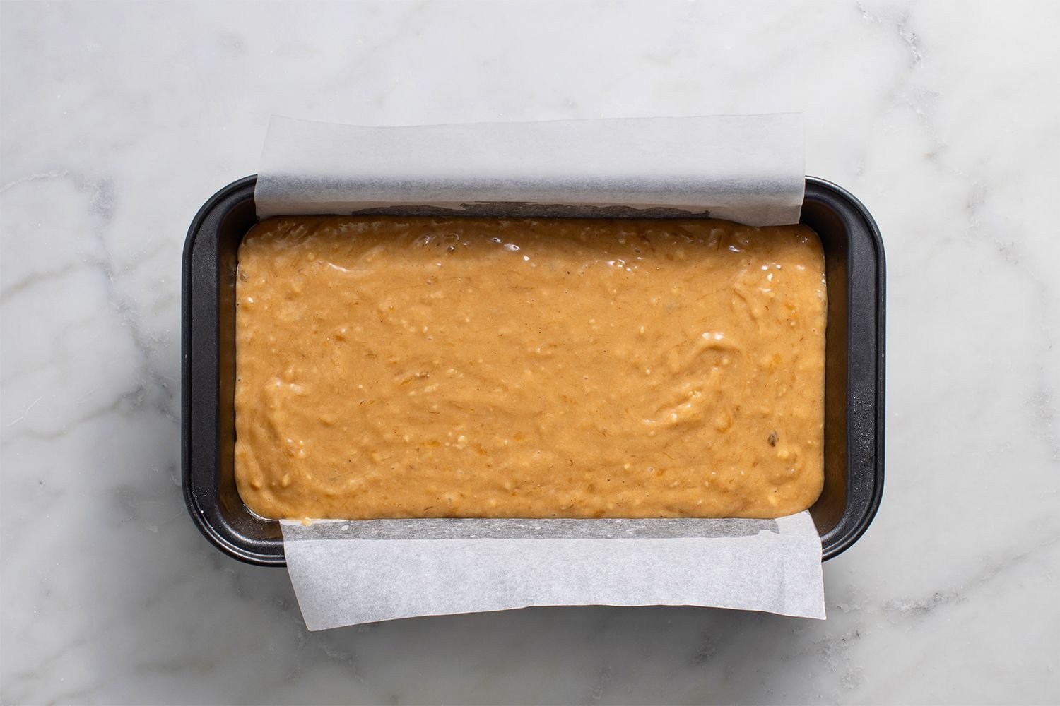 Batter in a parchment paper lined loaf pan
