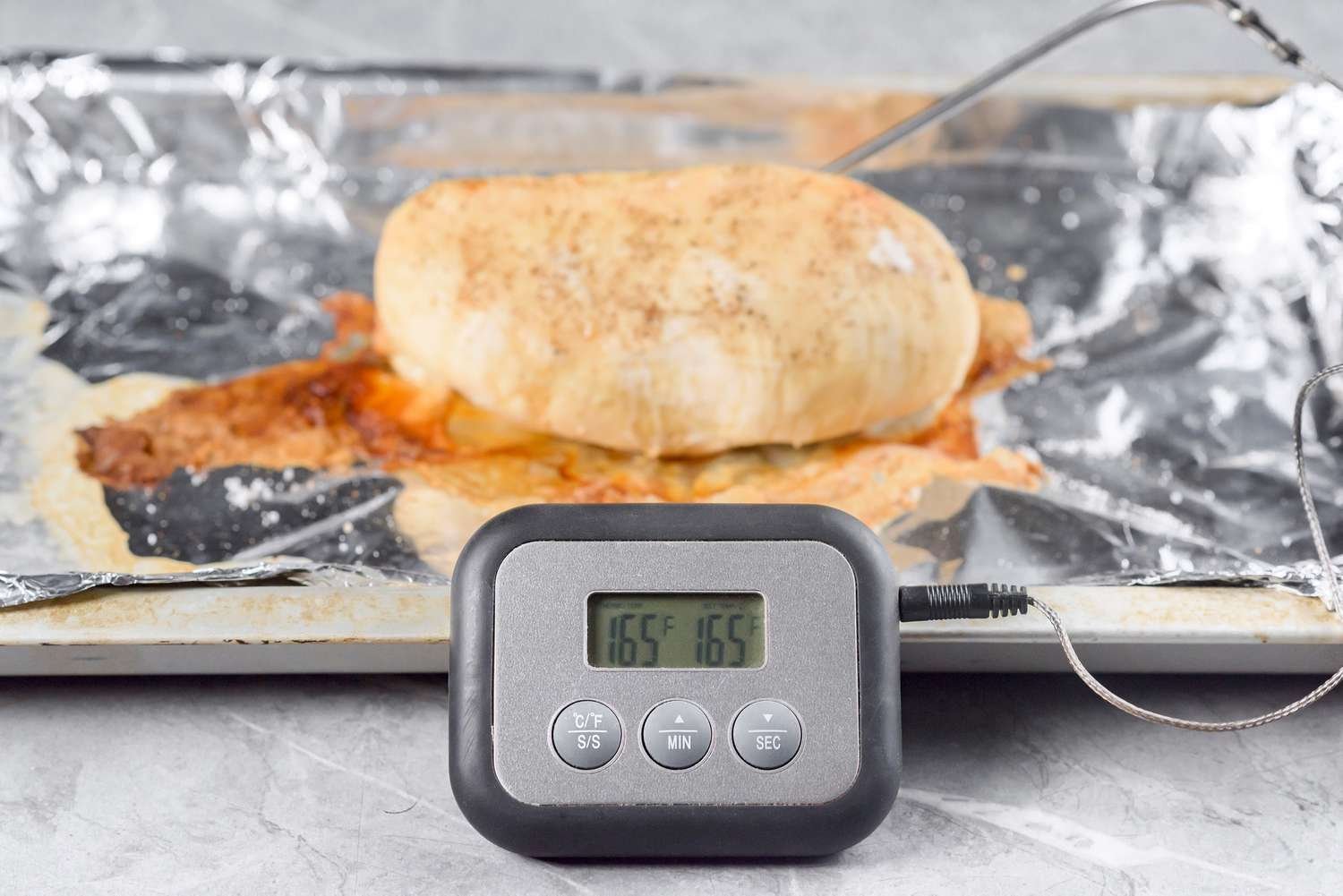 Pollo horneado con termómetro insertado, mostrando 165 grados Fahrenheit