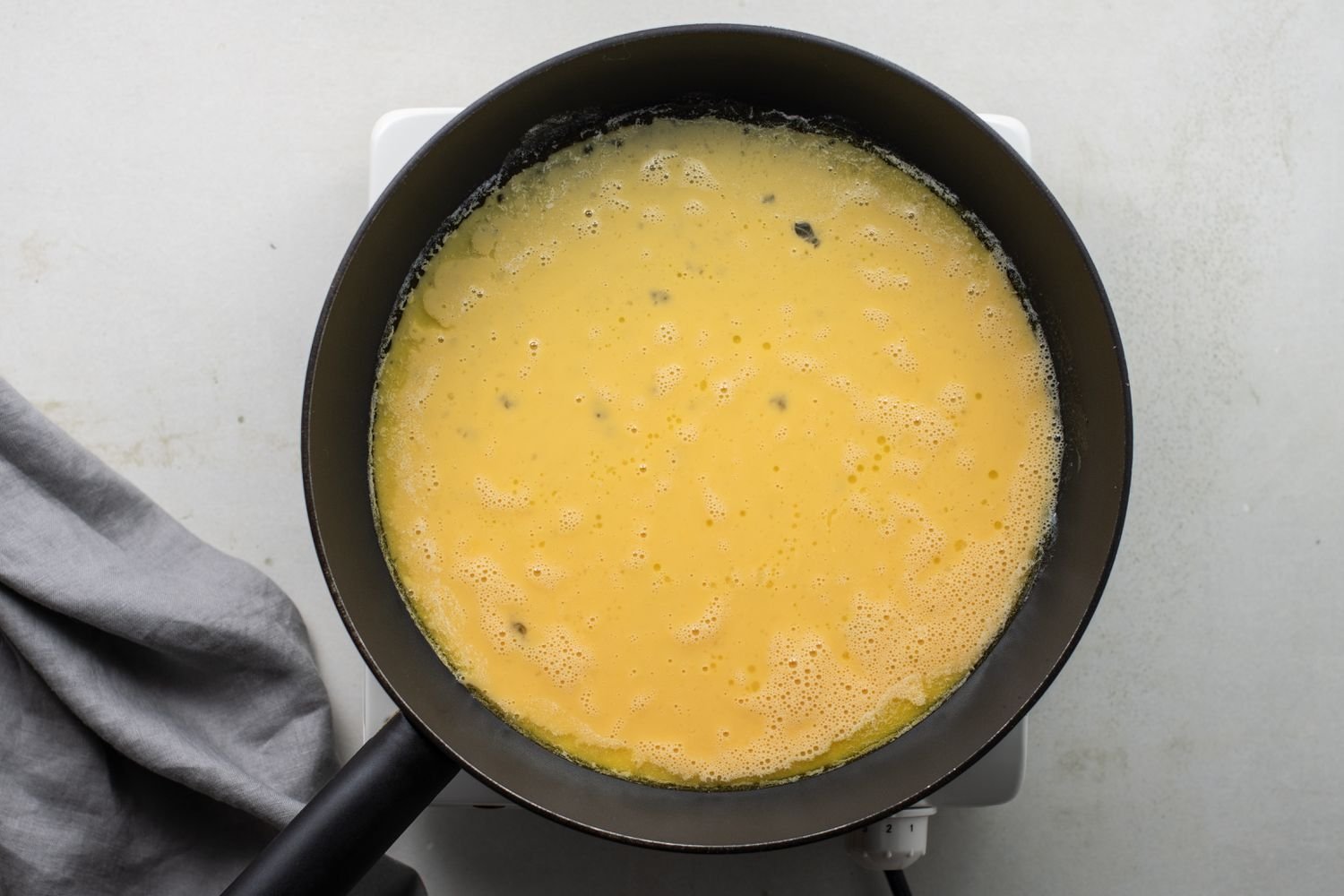 Huevos batidos cubriendo el fondo de la sartén