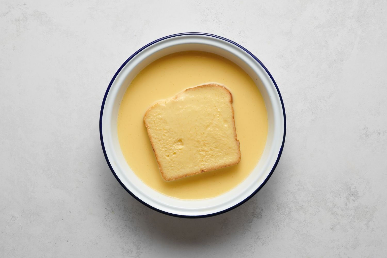 Un trozo de pan empapado en la mezcla de huevo y leche batidos