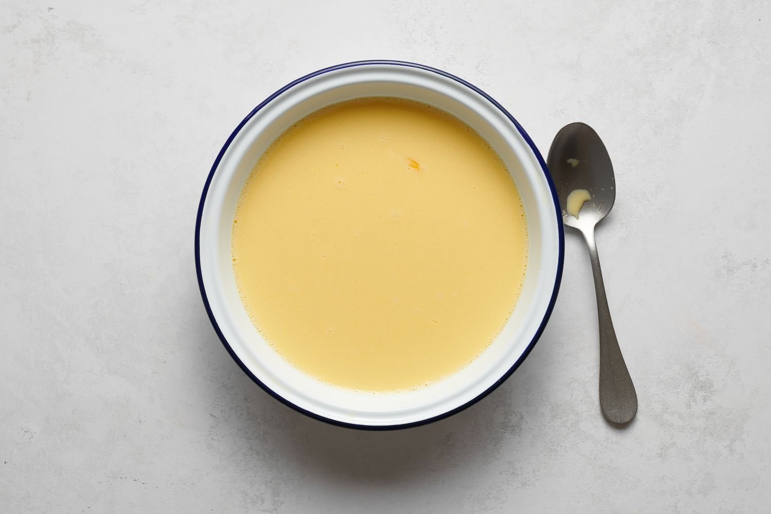 Un tazón de huevos batidos, leche, azúcar y sal