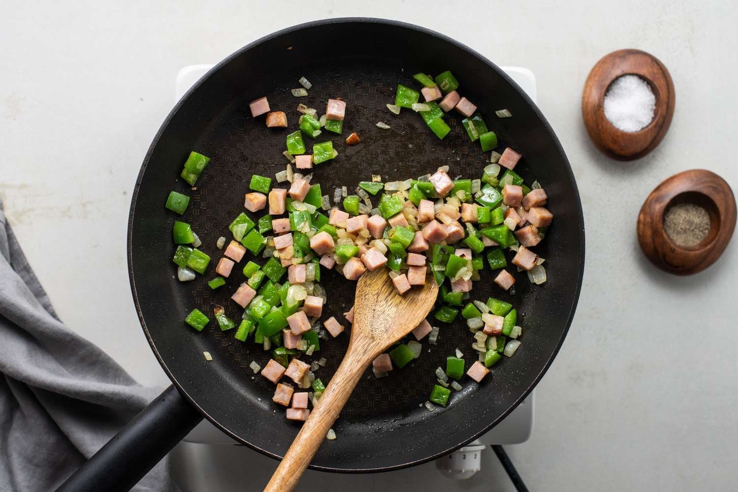 El jamón y el pimiento morrón siendo salteados en una sartén