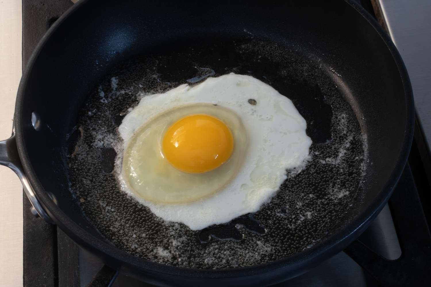 Huevo con yema intacta cocinándose en la sartén