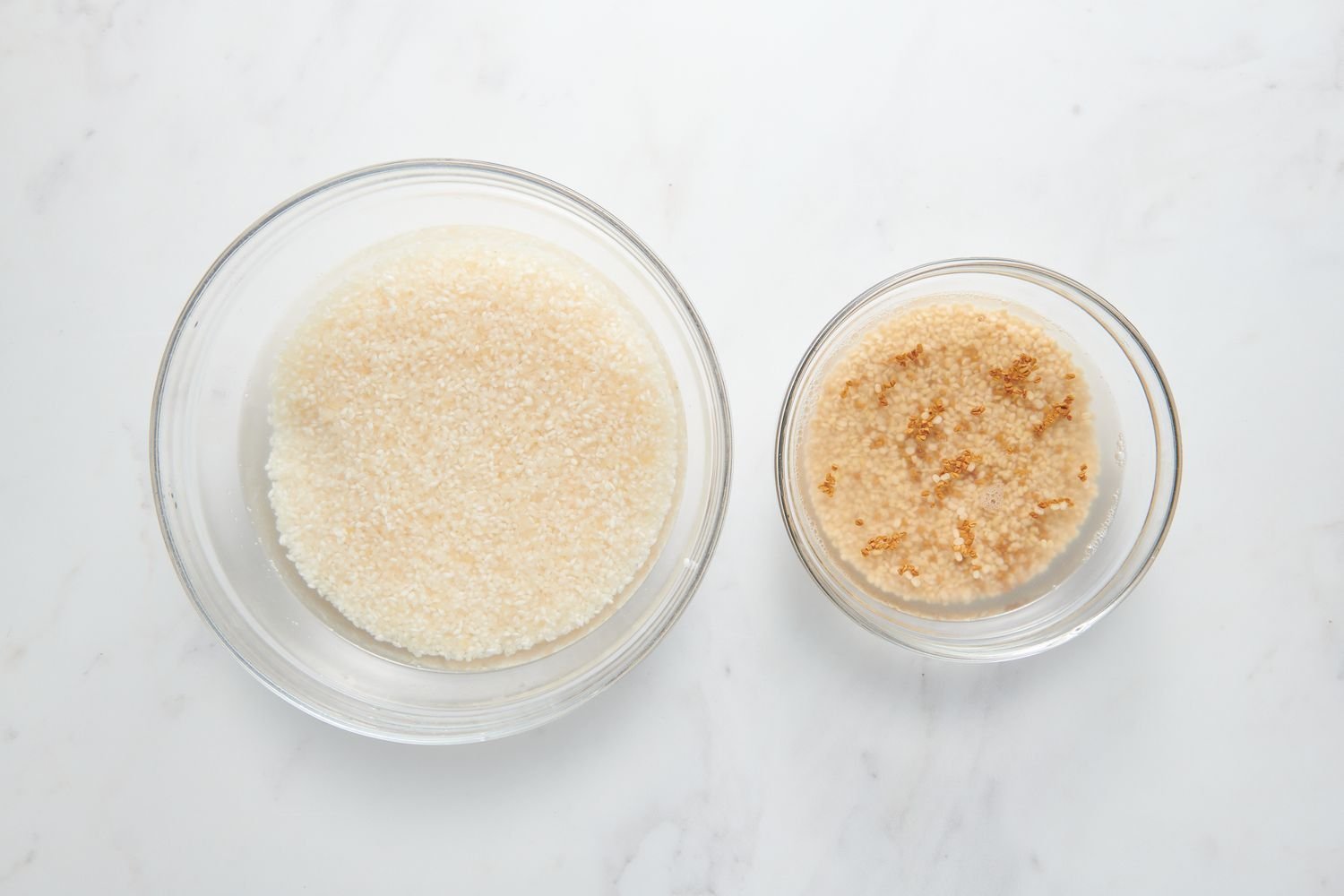 Un tazón de Sona Masuri en agua, y un tazón de urad dal y fenogreco en agua