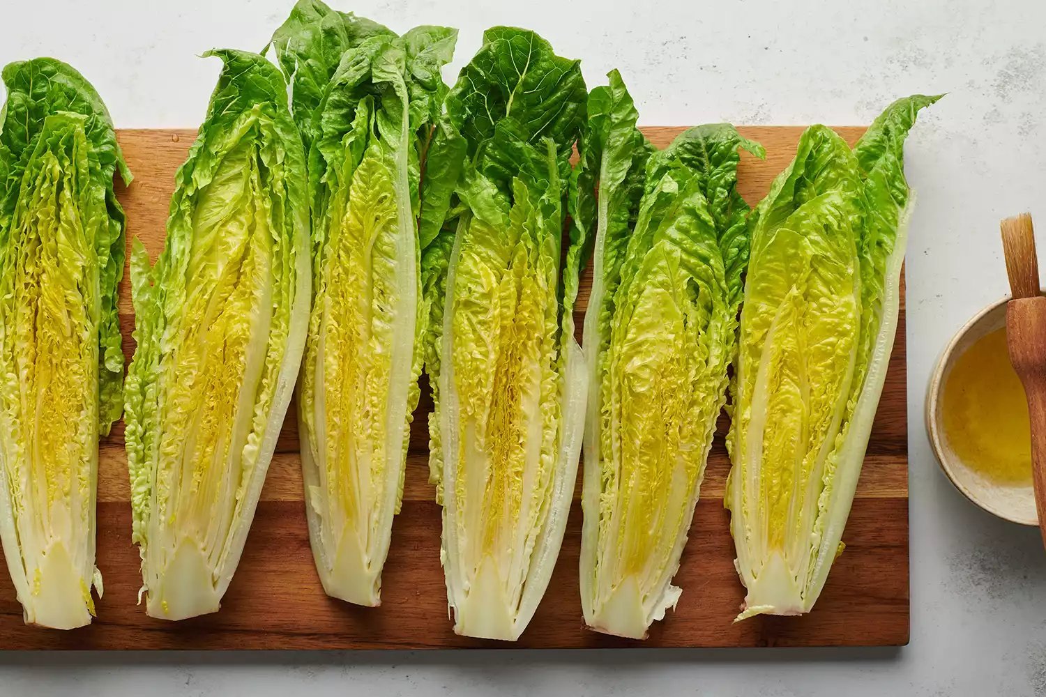 Alface fresca coberta de azeite em uma tábua de corte de madeira.