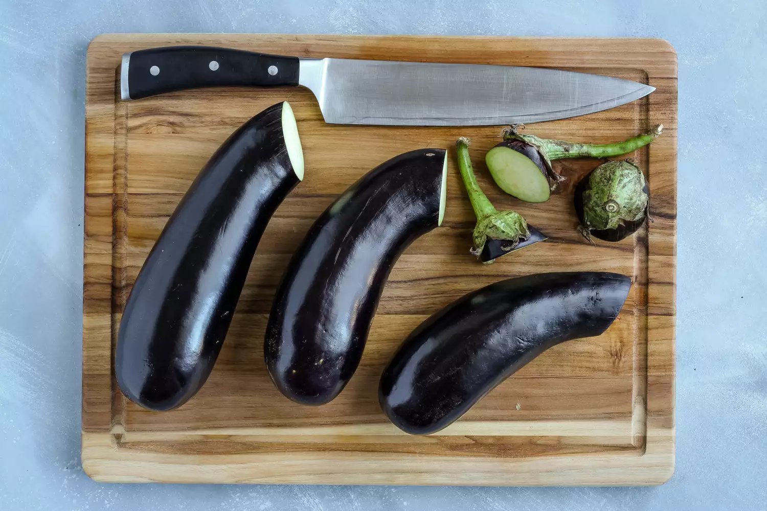 Extremidades do cabo descartadas da berinjela em uma tábua de cortar