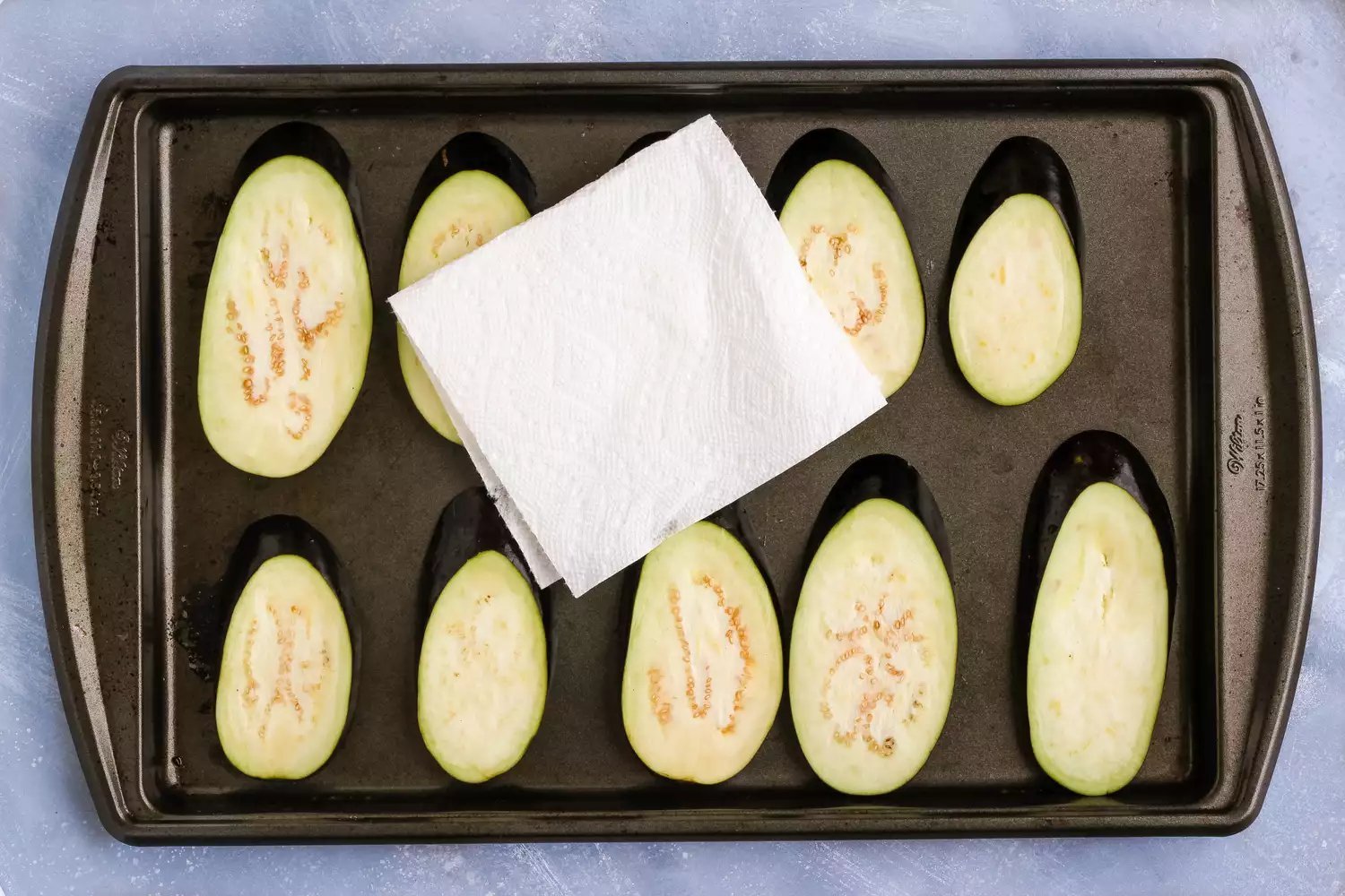 Secando a berinjela drenada em uma assadeira com bordas