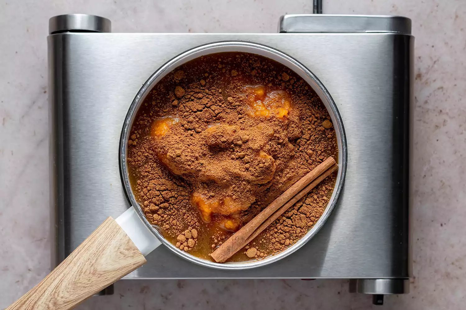 Abóbora, cidra de maçã, xarope de bordo, especiarias de torta de abóbora, sal e canela em uma panela no fogão