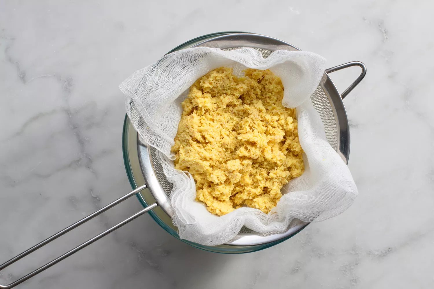 Shot de gengibre drenando através de uma peneira forrada de pano