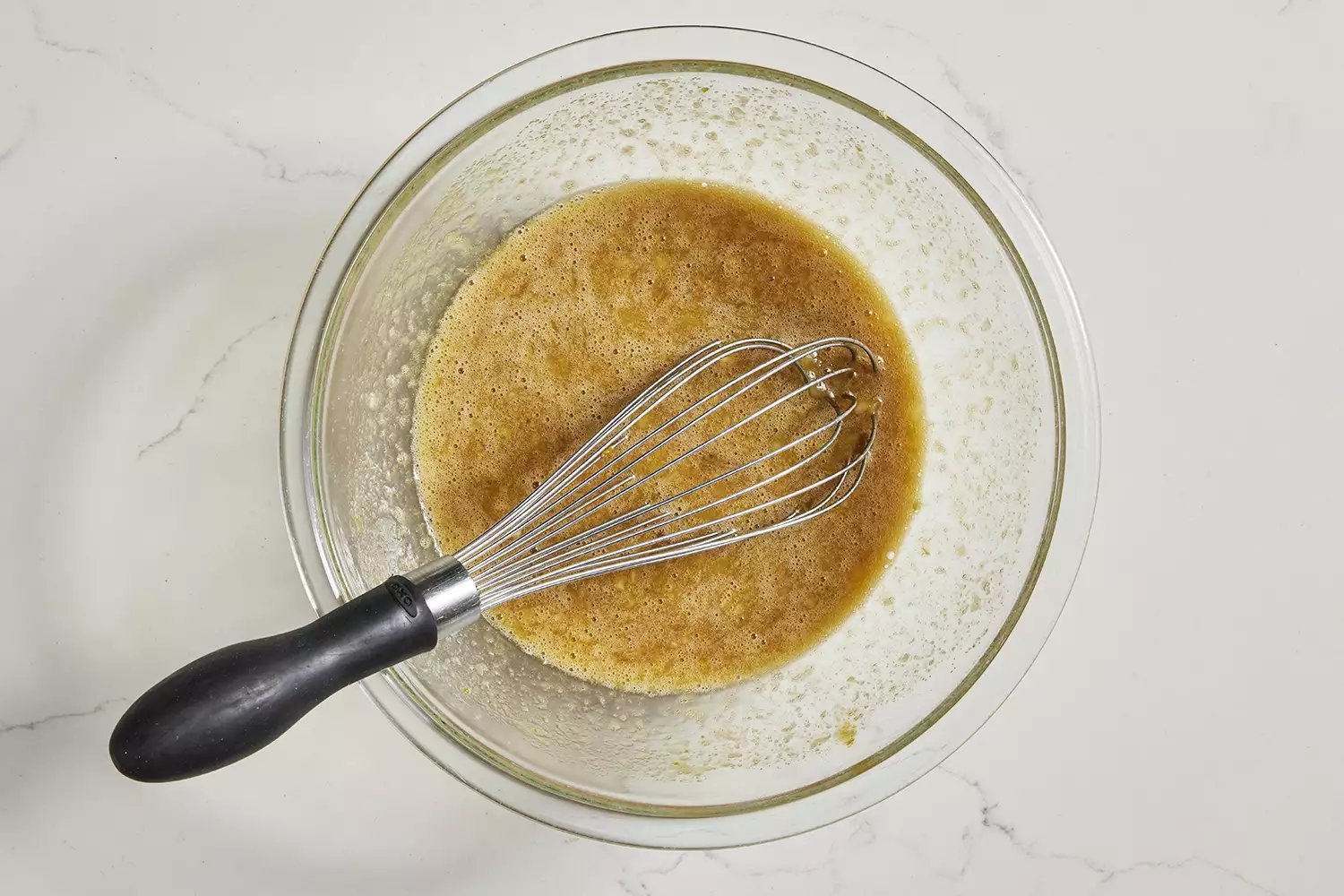 ingredientes molhados para o pão de banana com abóbora em uma tigela com um batedor