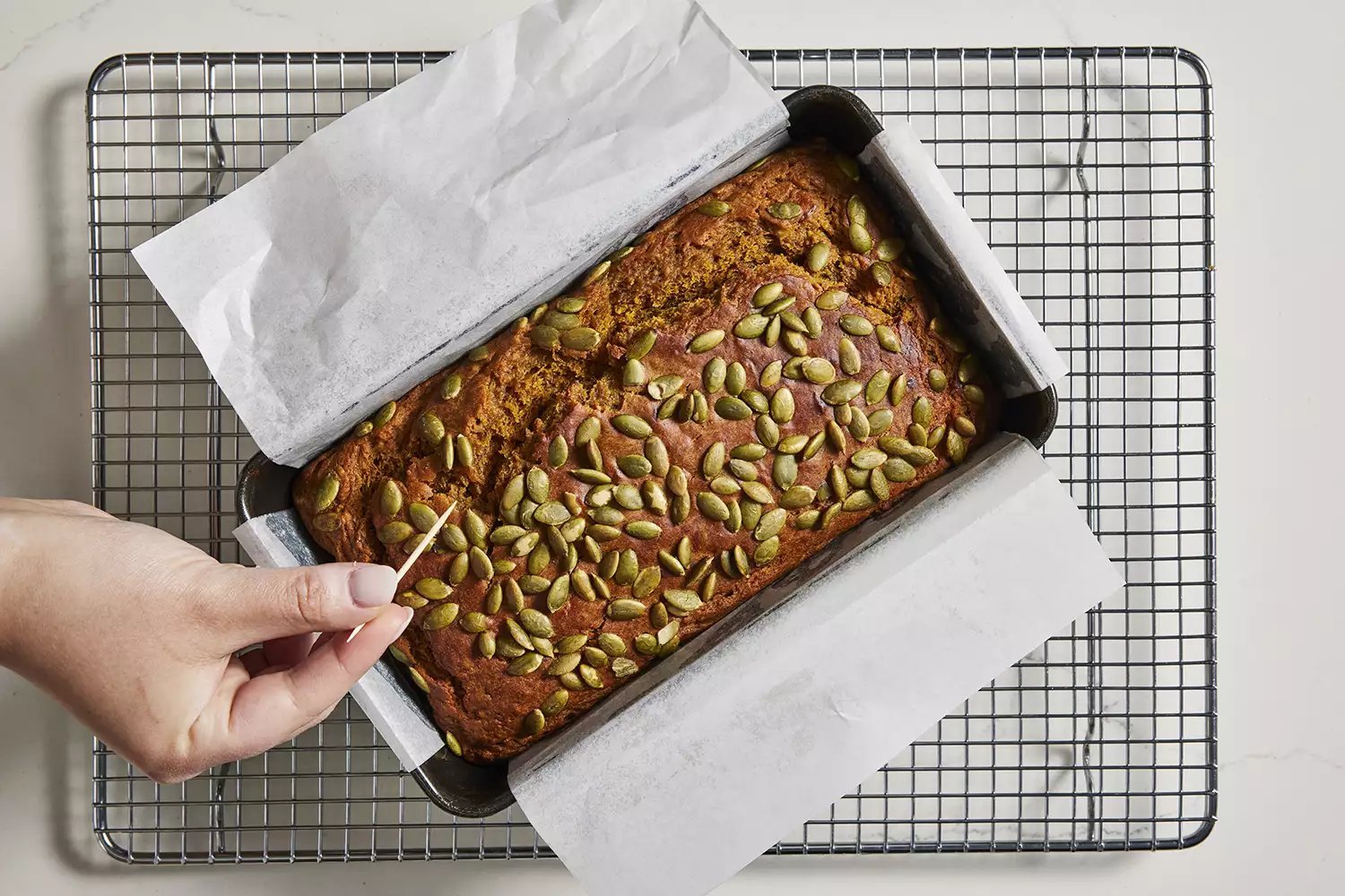 pão de banana com abóbora em uma grade, testando com palito