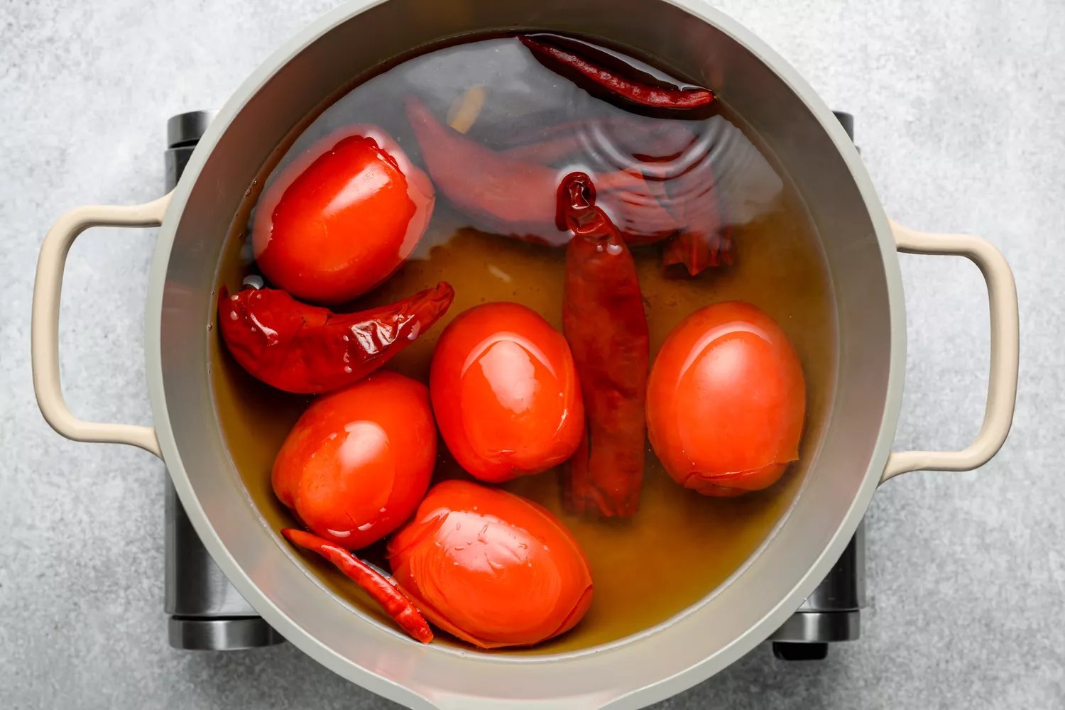 Uma panela com água e chiles guajillo, chile de arbol, tomates Roma e alho
