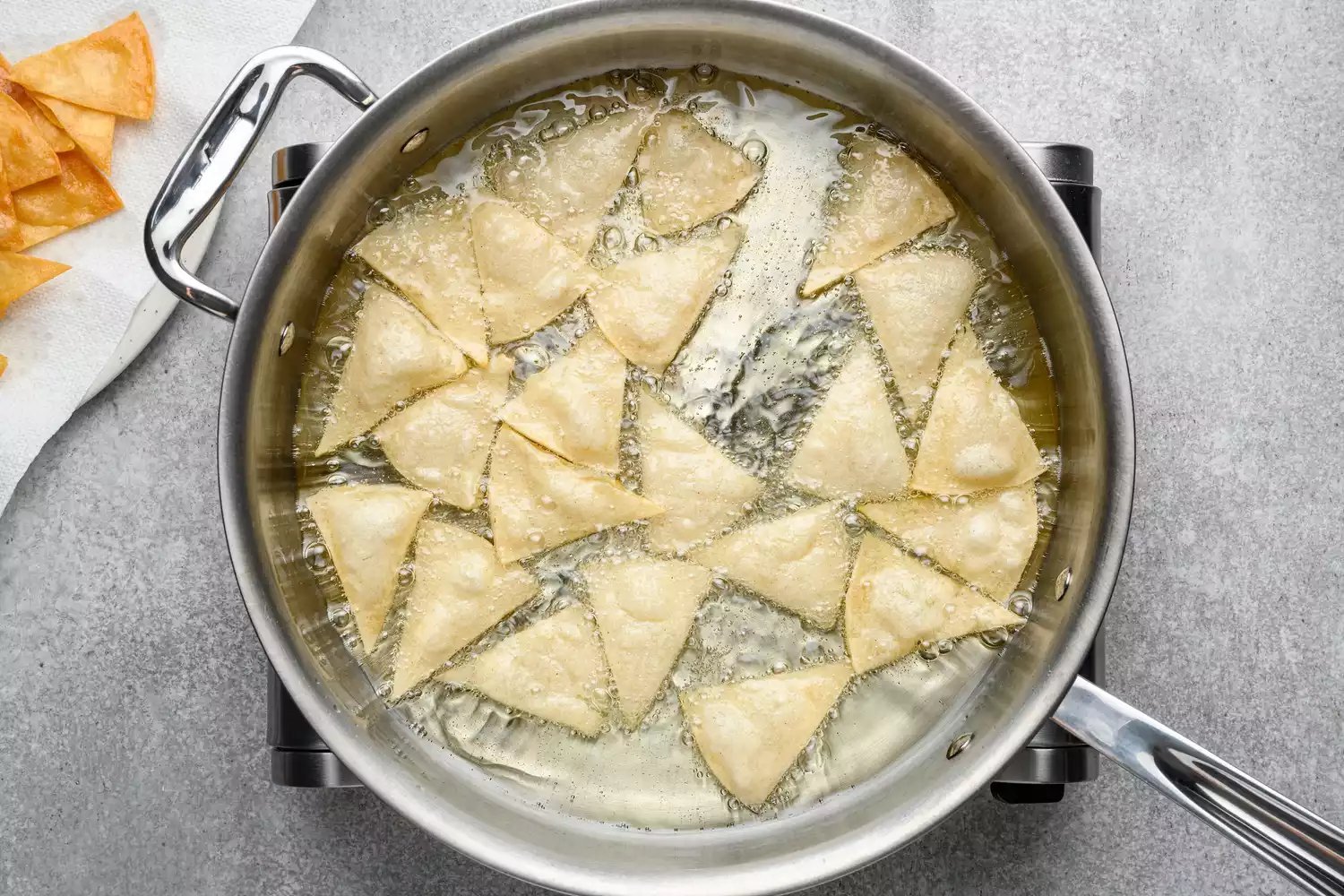 Triângulos de tortillas fritando em uma panela com óleo
