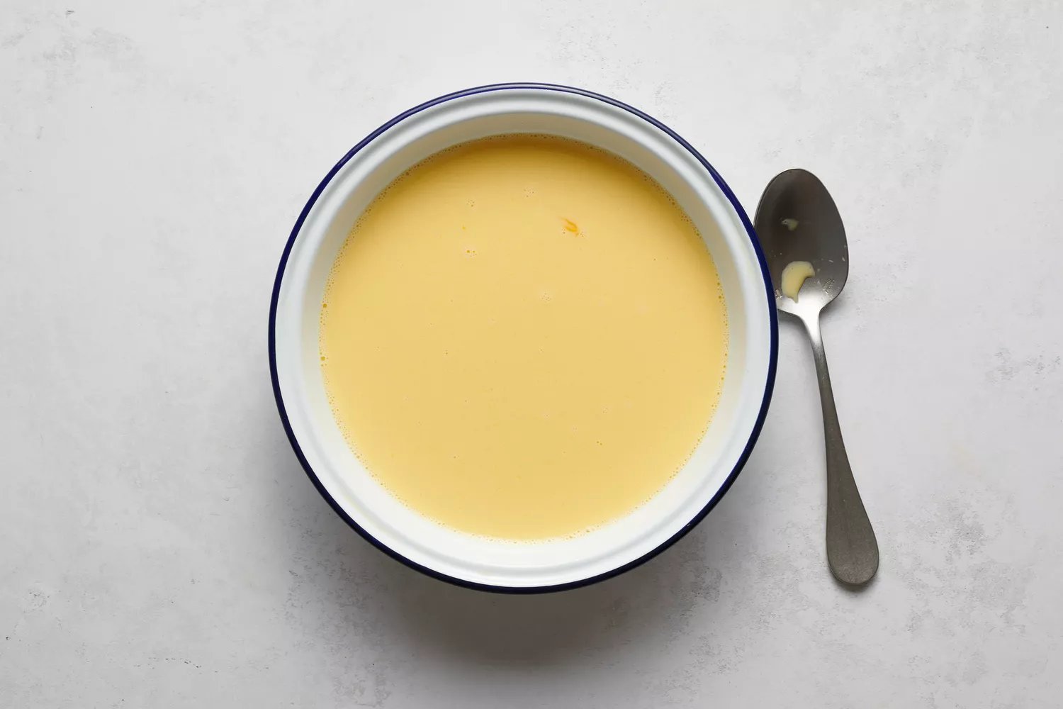 Uma tigela de ovos batidos, leite, açúcar e sal