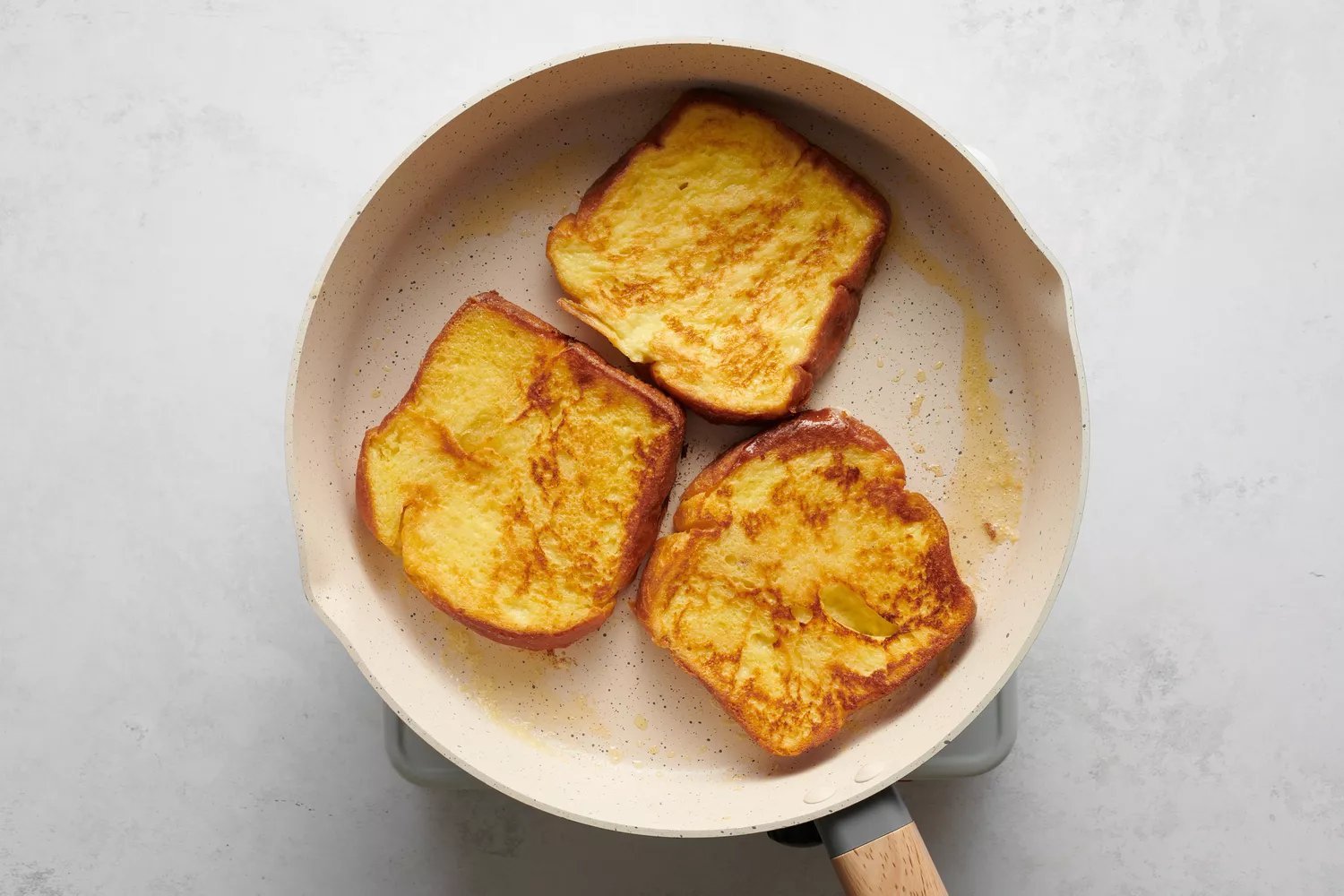 Três pedaços de torrada francesa cozinhando em uma panela